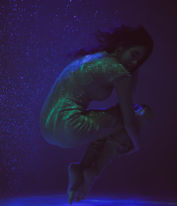 Woman in a serene yoga pose against a calm, dark background with light blue accents.